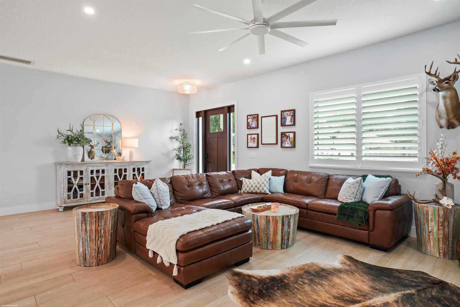 A living room features a brown leather sectional, rustic wooden tables, and a deer mount — 4255 79th Street, Vero Beach FL 32967, VERO BEACH, FL