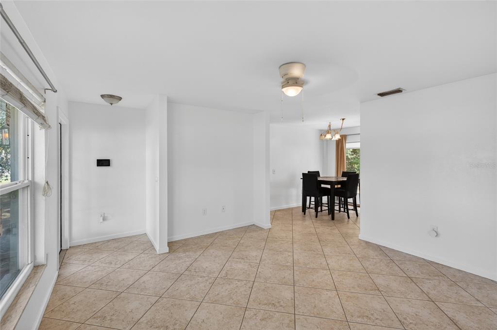 A tiled living area leads to a dining space with a table and chairs — 2025 BARKSDALE STREET, PORT CHARLOTTE, FL