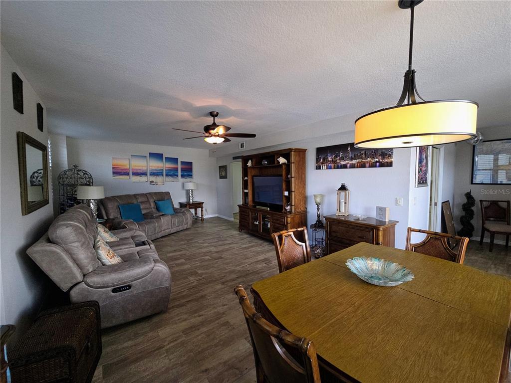 A living and dining area features wood-look tile flooring, a ceiling fan, and wooden furniture — 3820 GULF BOULEVARD UNIT 108, ST PETE BEACH, FL