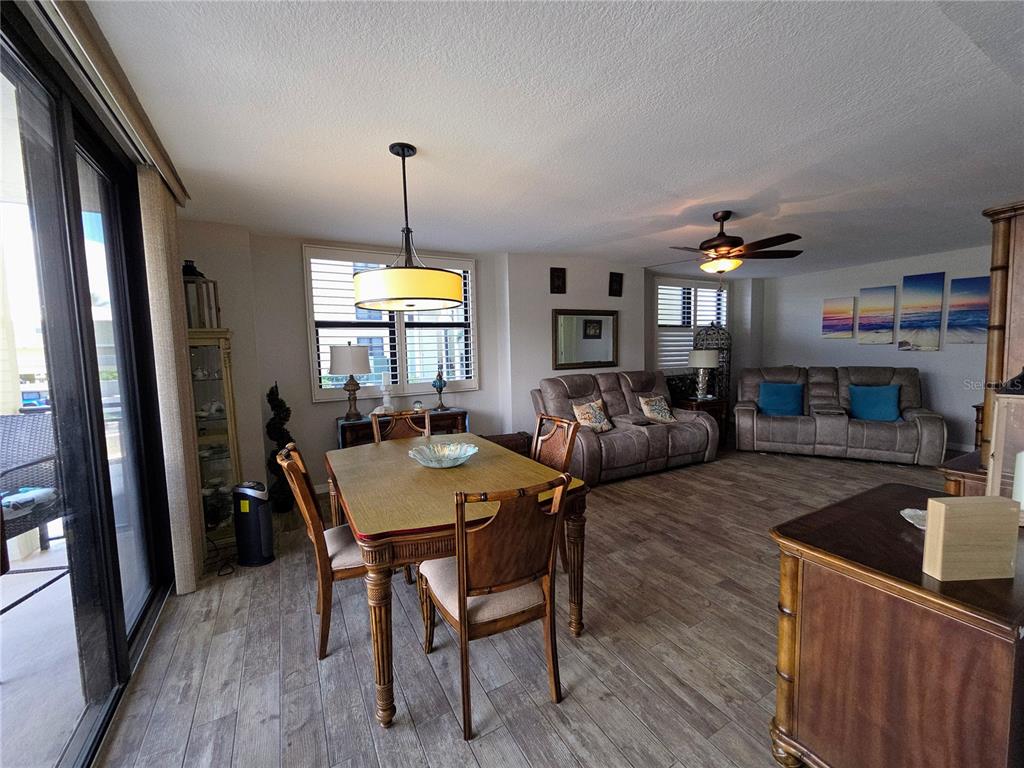 A dining area and living room with wood-look tile flooring and a ceiling fan — 3820 GULF BOULEVARD UNIT 108, ST PETE BEACH, FL