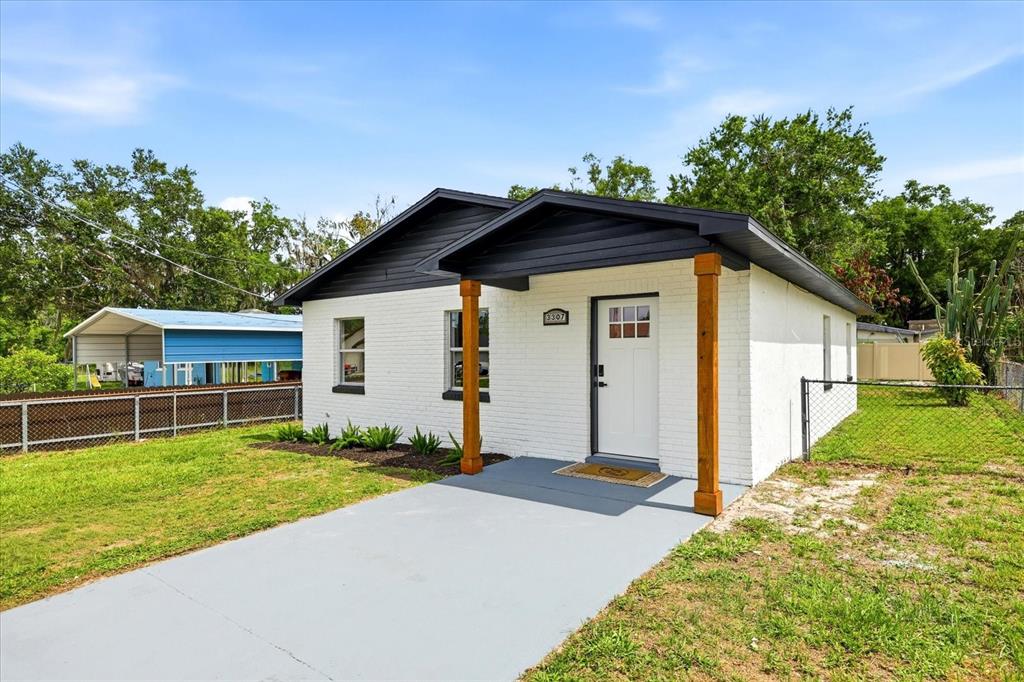 A white brick house with a dark roof and wooden porch posts sits on a lot — 3307 HICKMAN AVENUE, PLANT CITY, FL