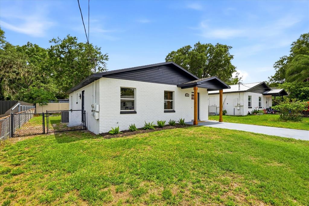 A white brick house with a dark roof and wooden porch posts sits on grass — 3307 HICKMAN AVENUE, PLANT CITY, FL