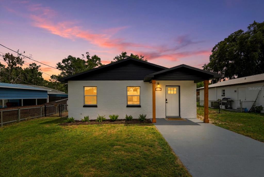 A single-story white brick house with a dark roof and wooden porch posts at sunset — 3307 HICKMAN AVENUE, PLANT CITY, FL