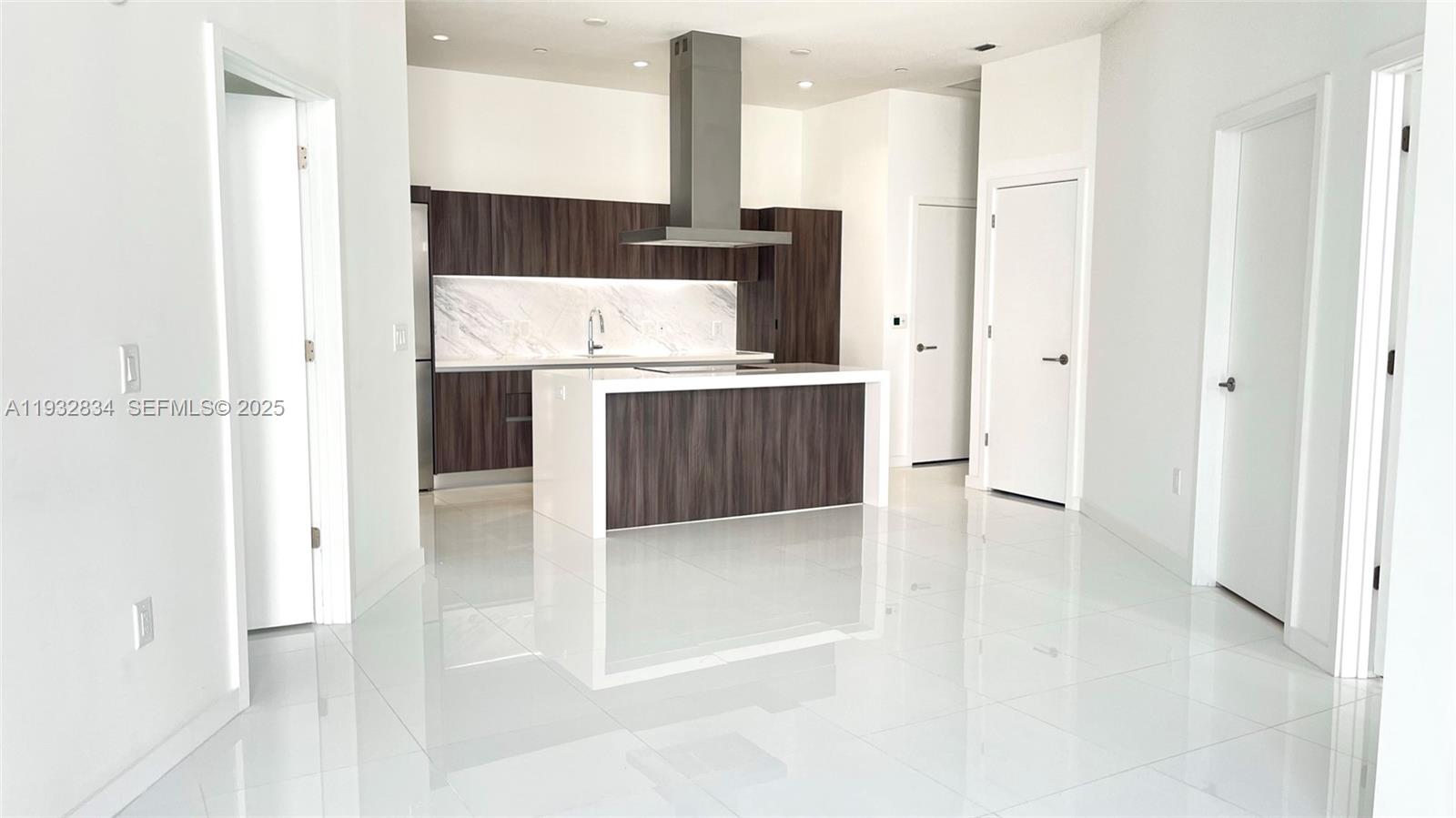 A modern kitchen features dark wood cabinetry, a white island, and a stainless steel hood — 851 NE 1st Ave # 412, Miami FL 33132, MIAMI, FL