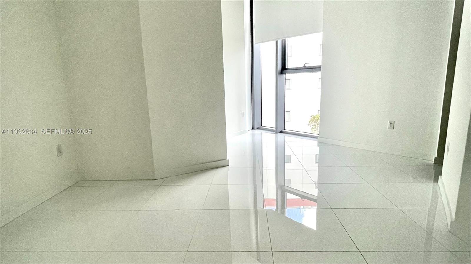 A bright, empty room features white walls, glossy tile flooring, and floor-to-ceiling windows — 851 NE 1st Ave # 412, Miami FL 33132, MIAMI, FL