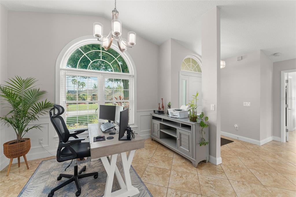 A home office with a large arched window, tile flooring, and a central desk — 917 VIA BIANCA DRIVE, DAVENPORT, FL