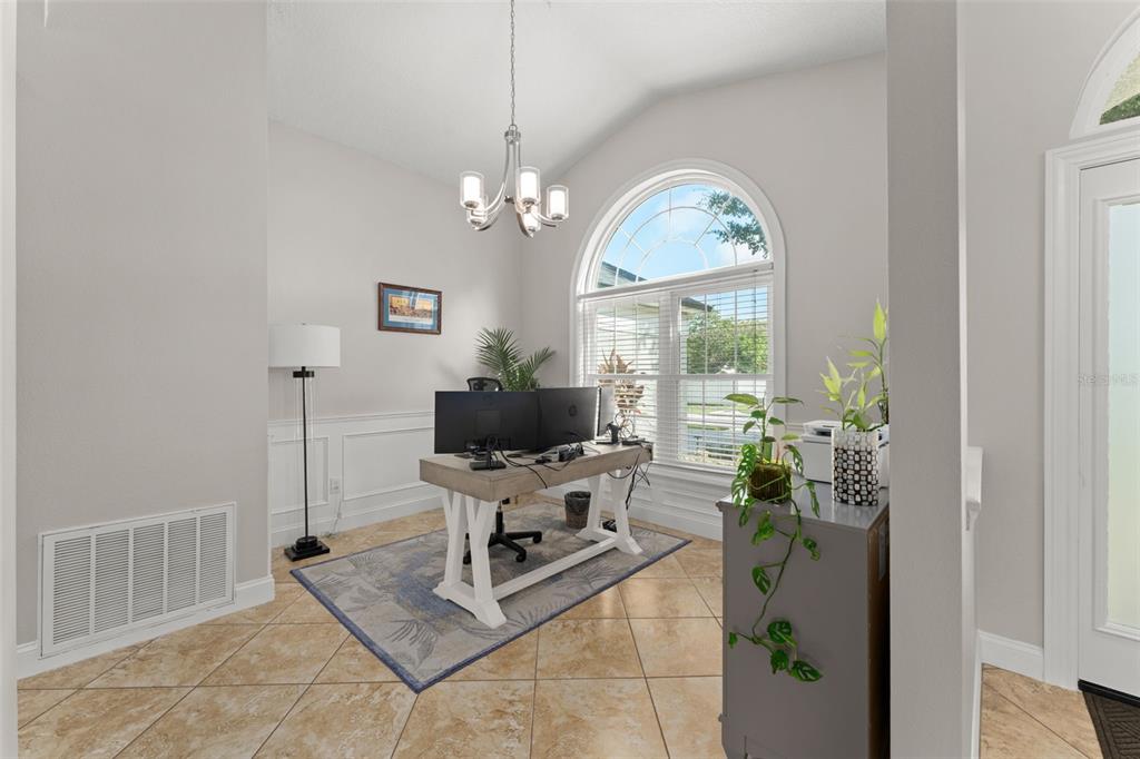 A home office features tile flooring, a large arched window, and a central wooden desk — 917 VIA BIANCA DRIVE, DAVENPORT, FL