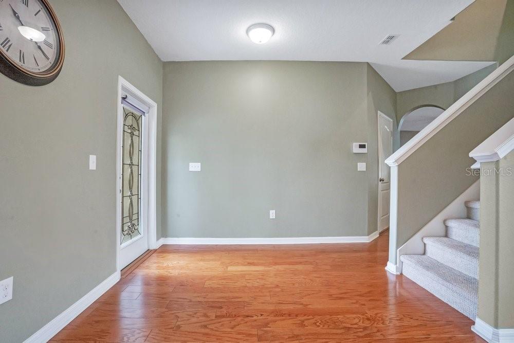 An entryway features hardwood floors, a staircase with carpeted steps, and a glass-paneled front door — 4847 HAVILLAND DRIVE, MOUNT DORA, FL