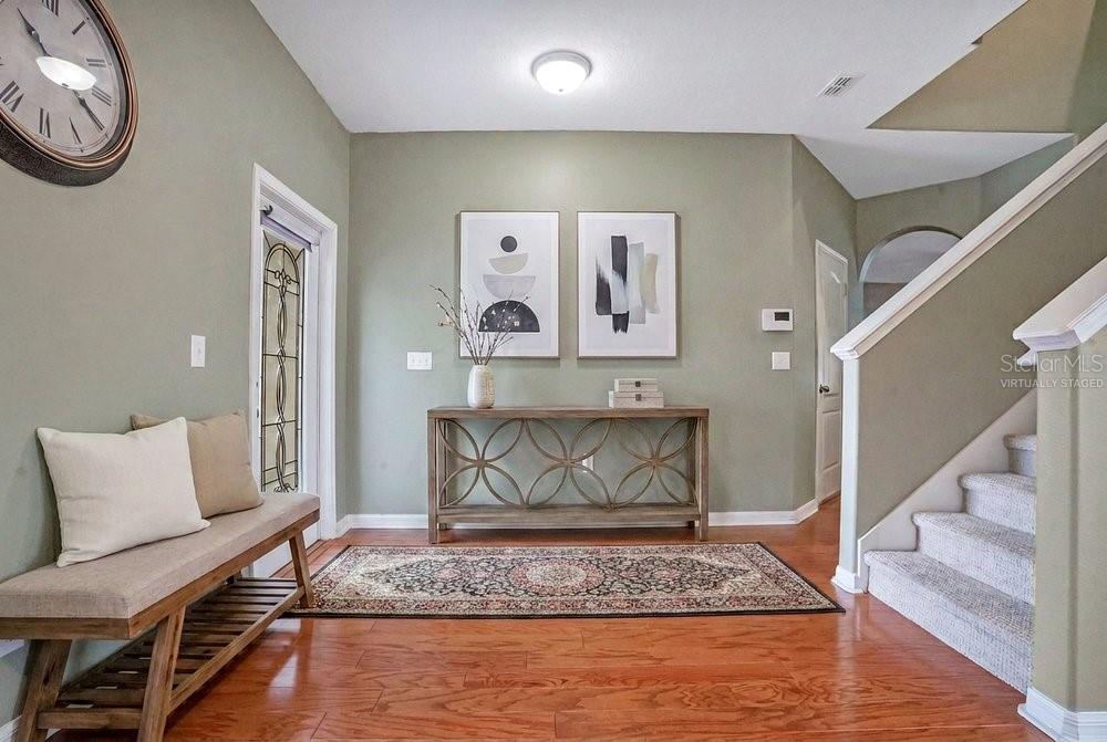 A foyer features hardwood floors, a console table, a bench, and a staircase with carpet — 4847 HAVILLAND DRIVE, MOUNT DORA, FL