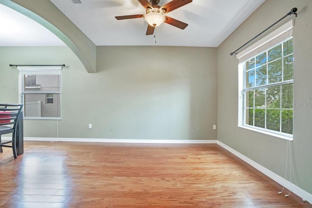 An empty room with light green walls, hardwood floors, a ceiling fan, and two windows — 4847 HAVILLAND DRIVE, MOUNT DORA, FL