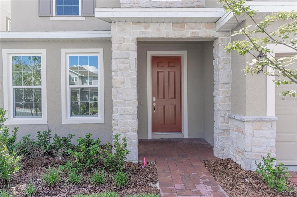 A front entryway with a red door, stone pillars, and a brick walkway — 5018 DOWN COURT, ST CLOUD, FL