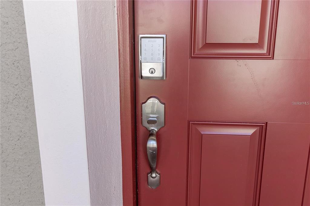 A close-up view of a red front door with a silver electronic keypad and handle — 5018 DOWN COURT, ST CLOUD, FL