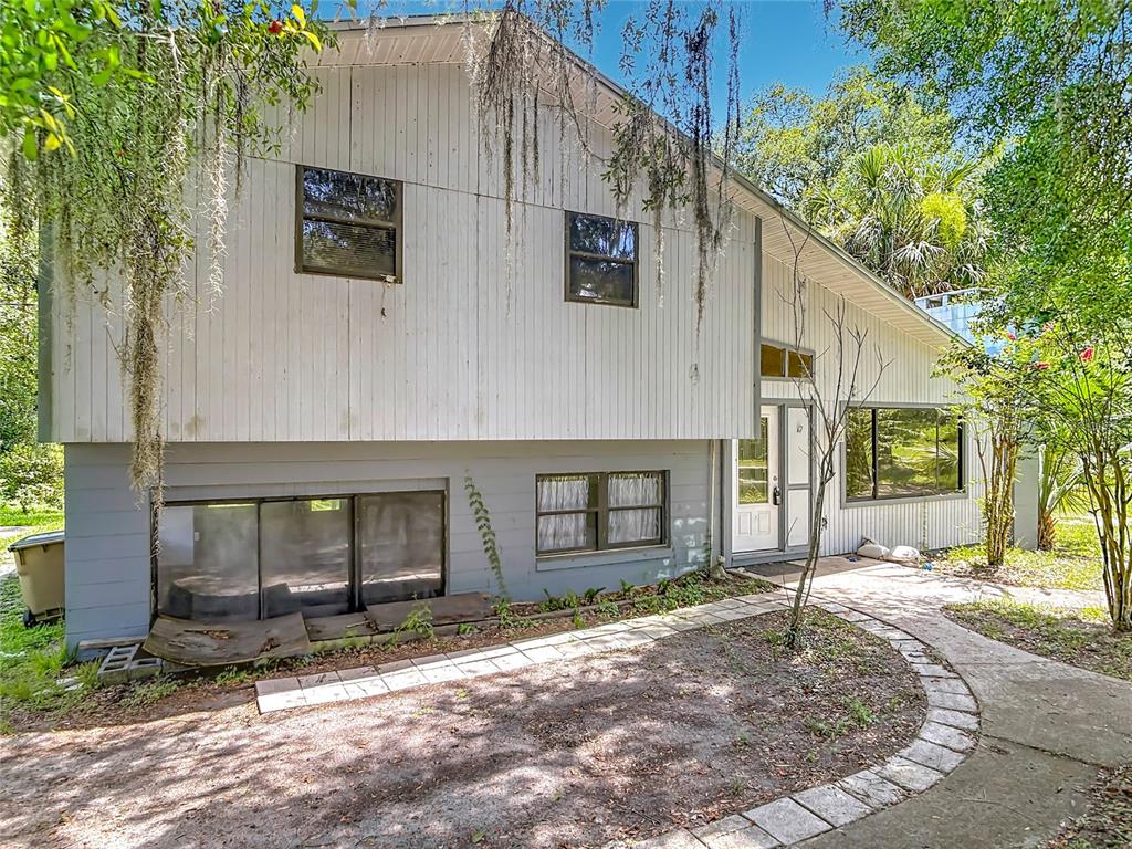 A two-story house with white vertical siding, a gray lower level, and a curved walkway — 24930 AVENUE C, PAISLEY, FL