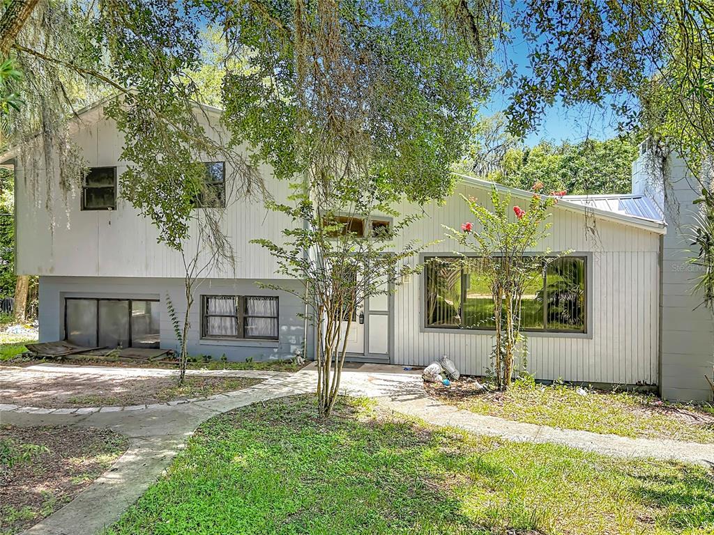 A two-story house with white vertical siding, a metal roof, and a concrete walkway — 24930 AVENUE C, PAISLEY, FL