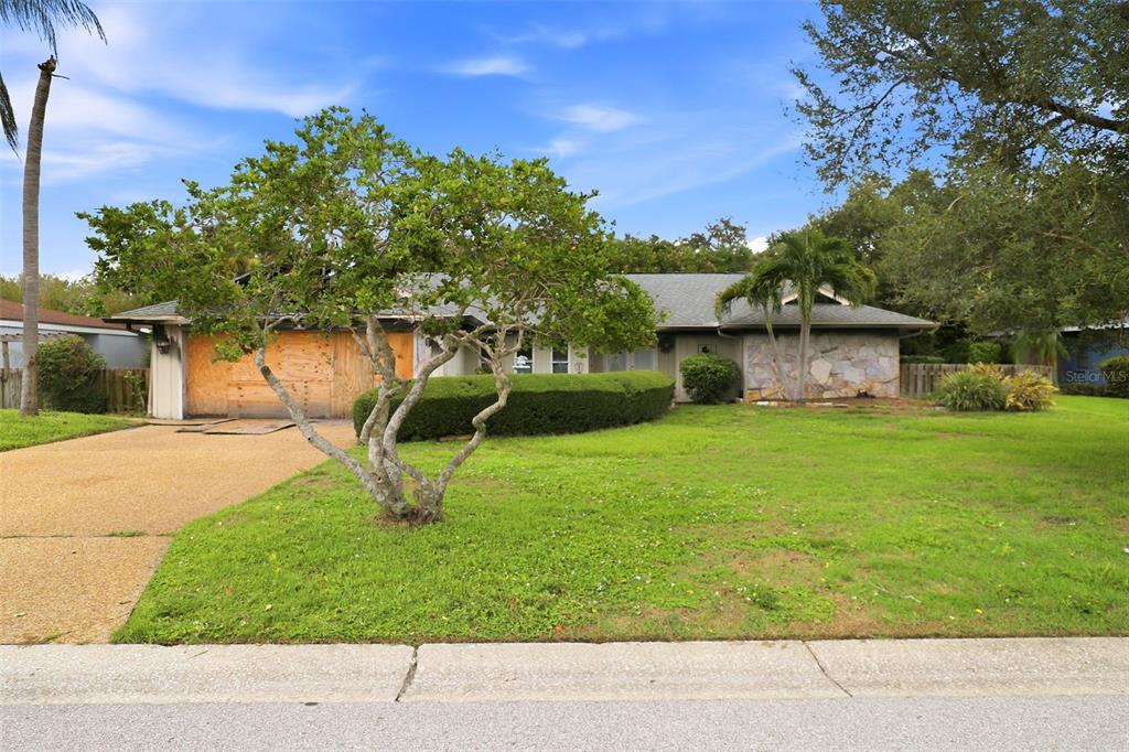 A single-story house with a stone facade, boarded-up garage, and a large front lawn — 3745 COUNTRYSIDE ROAD, SARASOTA, FL