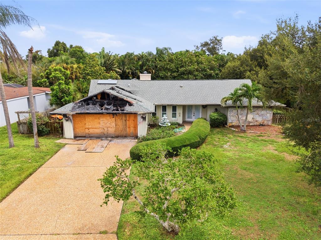 An exterior view of a single-story house with a fire-damaged garage and boarded-up doors — 3745 COUNTRYSIDE ROAD, SARASOTA, FL