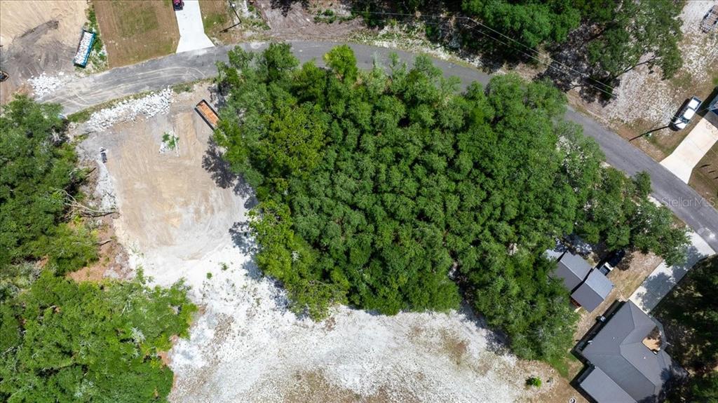 An aerial view shows a cleared construction lot surrounded by dense trees and paved roads — FISHER LANE COURT, OCKLAWAHA, FL