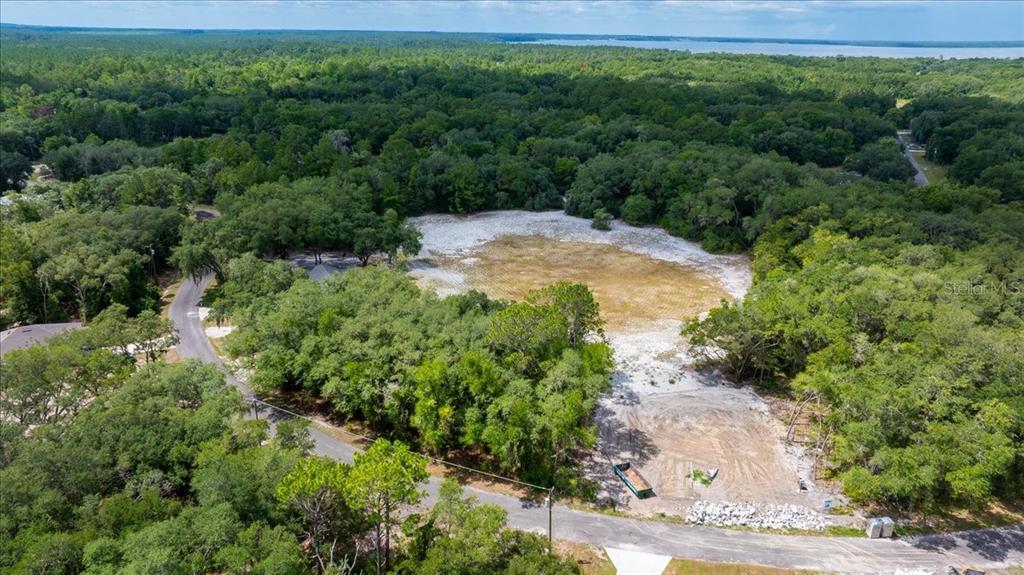 An aerial view shows a cleared, sandy residential lot surrounded by dense trees and vegetation — FISHER LANE COURT, OCKLAWAHA, FL