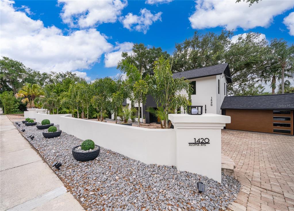 A modern two-story house features a white stucco wall, gravel landscaping, and a wooden garage — 1420 ALOMA AVENUE, WINTER PARK, FL