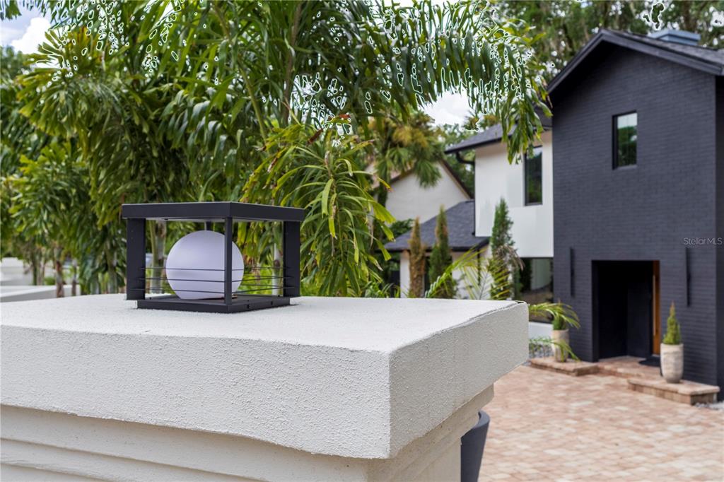 A modern black house is visible behind a white stucco pillar with a square light — 1420 ALOMA AVENUE, WINTER PARK, FL