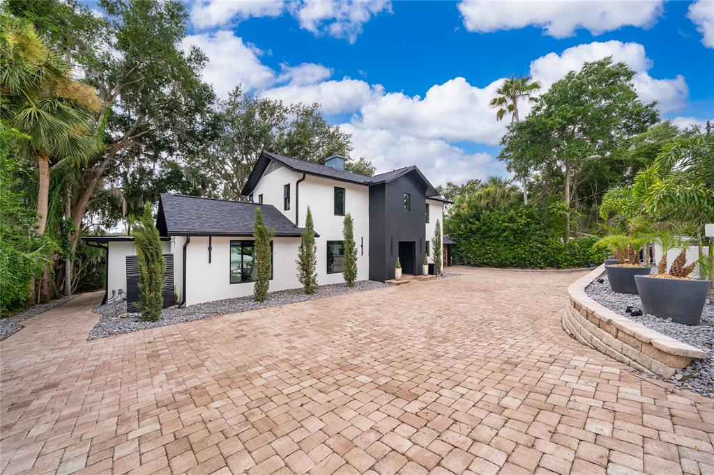 A modern two-story house with white and black exterior walls sits beside a paved driveway — 1420 ALOMA AVENUE, WINTER PARK, FL