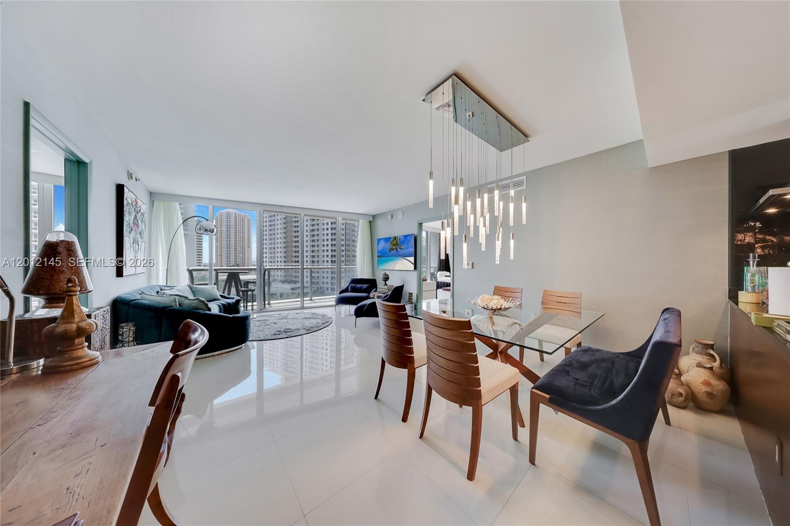 A modern dining and living area features a glass table, pendant lighting, and floor-to-ceiling windows — 465 Brickell Ave # 1019, Miami FL 33131, MIAMI, FL