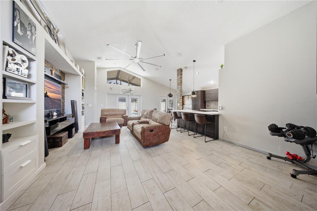 An open-concept living room features light tile flooring, a vaulted ceiling, and a kitchen island — 4321 BAYSIDE DRIVE, KISSIMMEE, FL