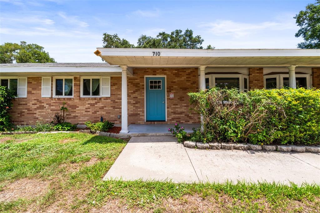 A single-story brick house features a blue front door and a covered concrete porch — 710 DEBRA LYNNE DRIVE, BRANDON, FL