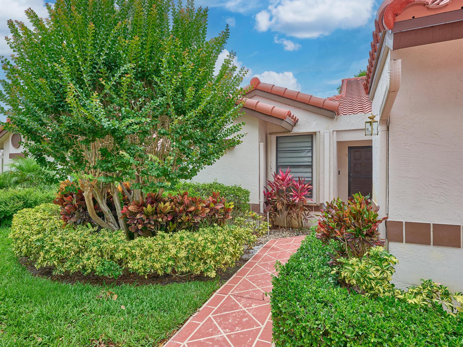A red tiled walkway leads to the front entrance of a house with landscaping — 6067 Kings Gate Circle, Delray Beach FL 33484, DELRAY BEACH, FL