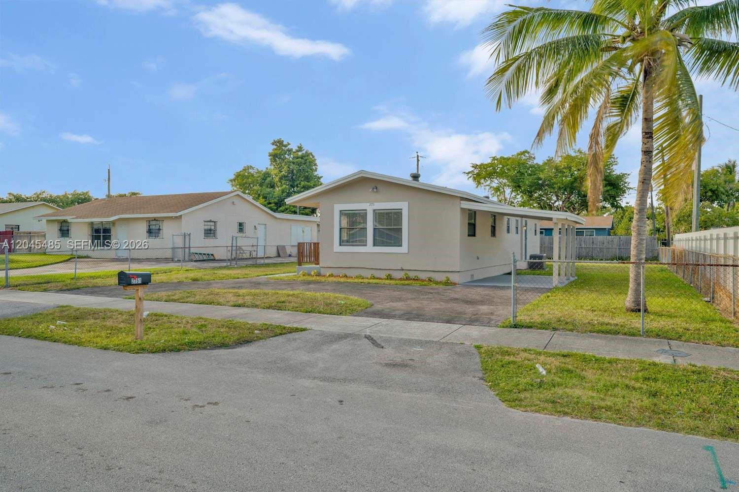 A single-story house with a beige exterior, a carport, and a palm tree in front — FORT LAUDERDALE, FL