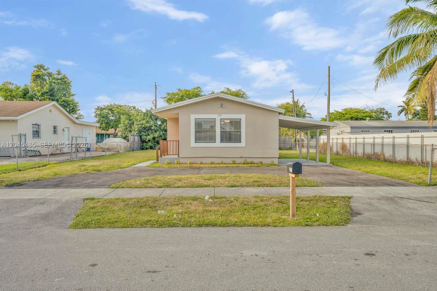 A single-story house with a beige exterior, a front carport, and a paved driveway — FORT LAUDERDALE, FL
