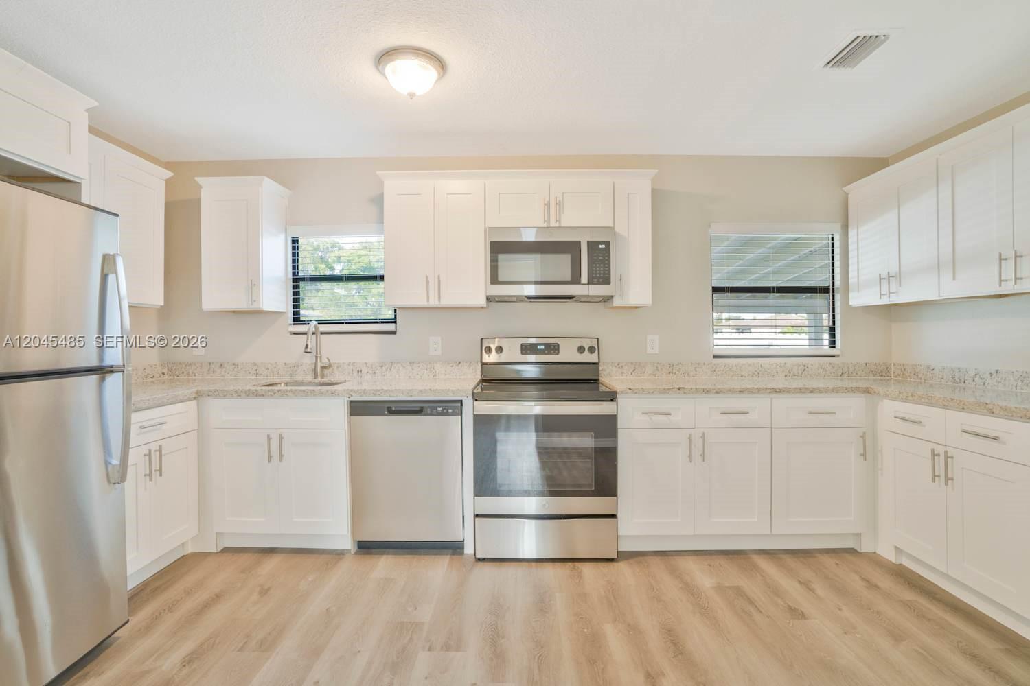 A kitchen features white cabinets, stainless steel appliances, and light-colored countertops — FORT LAUDERDALE, FL