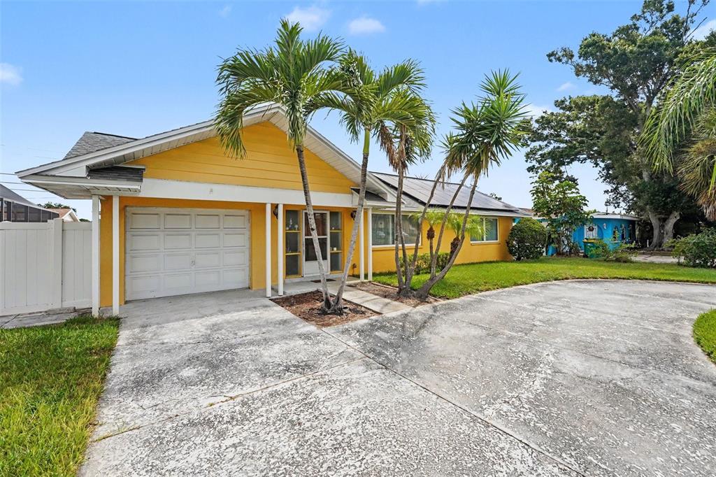 A yellow single-story house with a white garage door and palm trees in the front — 12149 PARK BOULEVARD UNIT 7, SEMINOLE, FL