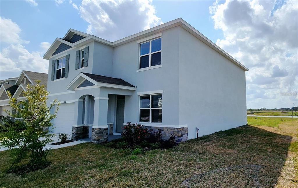 A two-story house with light blue stucco, stone accents, and a front-facing garage — 32813 OSPREY PEAK WAY, SAN ANTONIO, FL