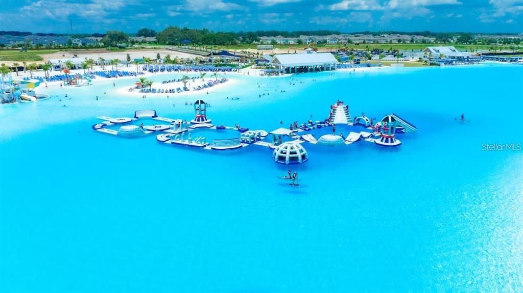 An aerial view shows a large blue lagoon with an inflatable obstacle course for swimmers — 32813 OSPREY PEAK WAY, SAN ANTONIO, FL