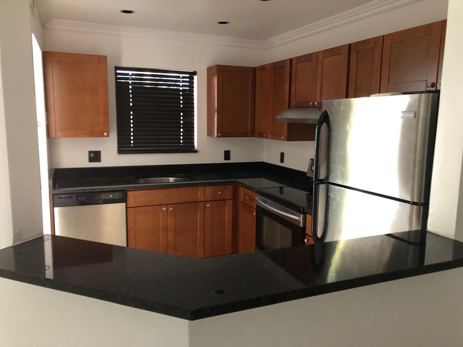 A kitchen with wood cabinets, black countertops, stainless steel appliances, and a breakfast bar — 21911 Lake Forest Circle # 204, Boca Raton FL 33433, BOCA RATON, FL