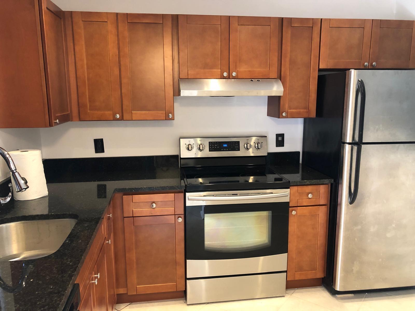A kitchen features wood cabinets, black granite countertops, and stainless steel appliances — 21911 Lake Forest Circle # 204, Boca Raton FL 33433, BOCA RATON, FL