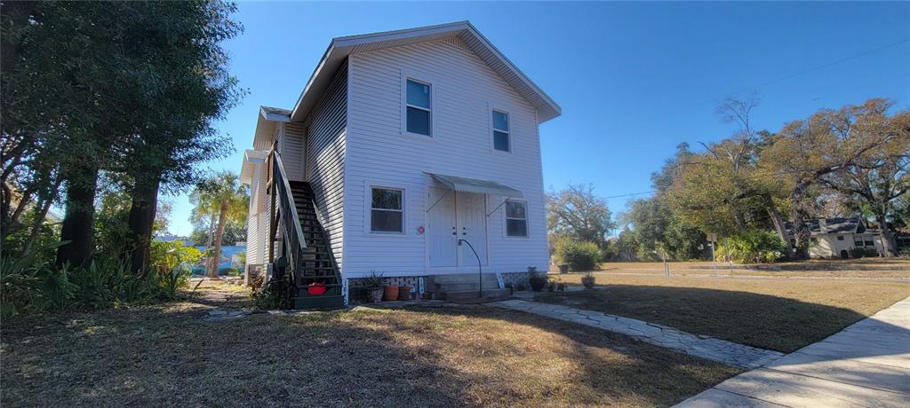 A two-story white house with vinyl siding features an exterior staircase and a stone walkway — 1846 2ND AVENUE N, ST PETERSBURG, FL