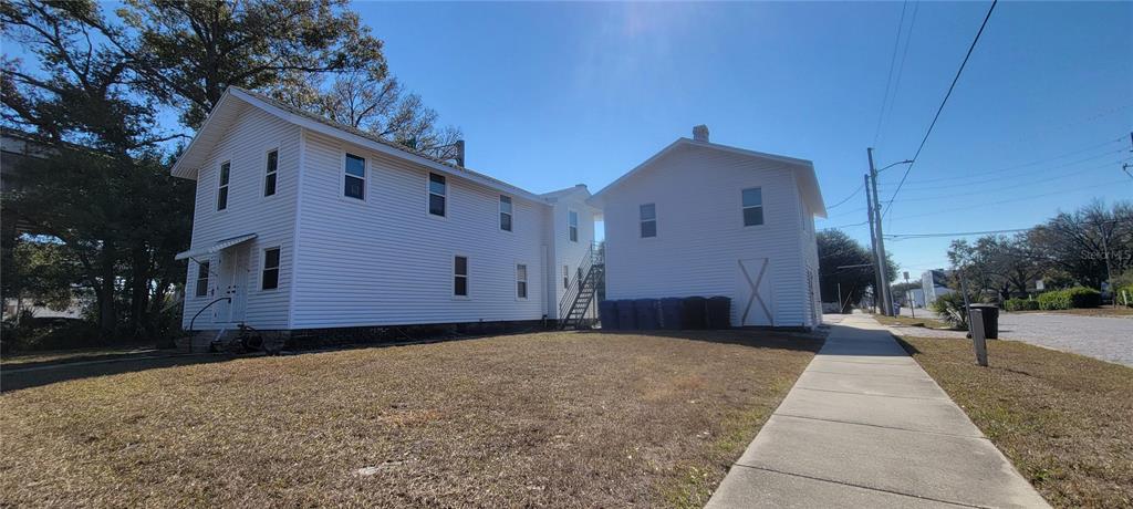 A two-story white house with vinyl siding stands next to a sidewalk and lawn — 1846 2ND AVENUE N, ST PETERSBURG, FL