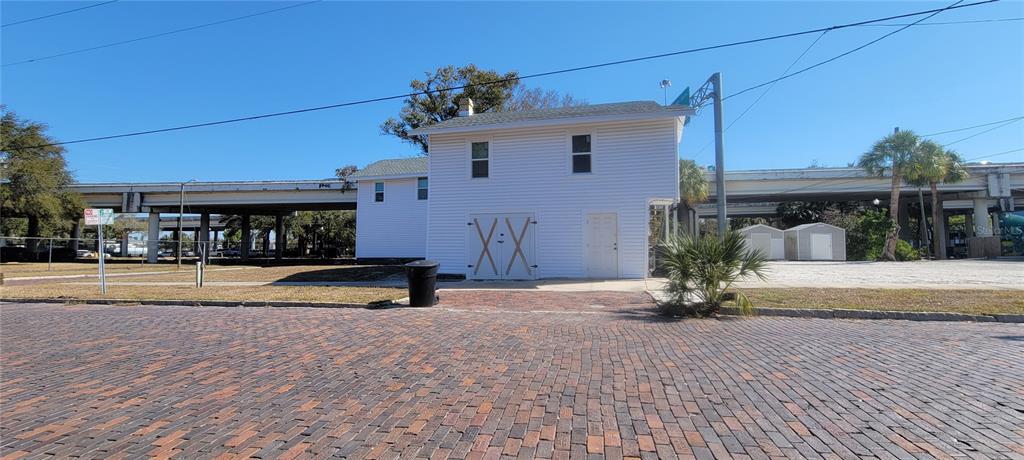A white two-story building with a brick-paved foreground sits beneath an elevated highway overpass — 1846 2ND AVENUE N, ST PETERSBURG, FL