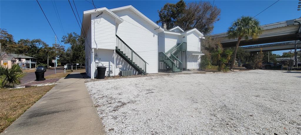 A white two-story building with exterior staircases sits next to a gravel parking lot — 1846 2ND AVENUE N, ST PETERSBURG, FL