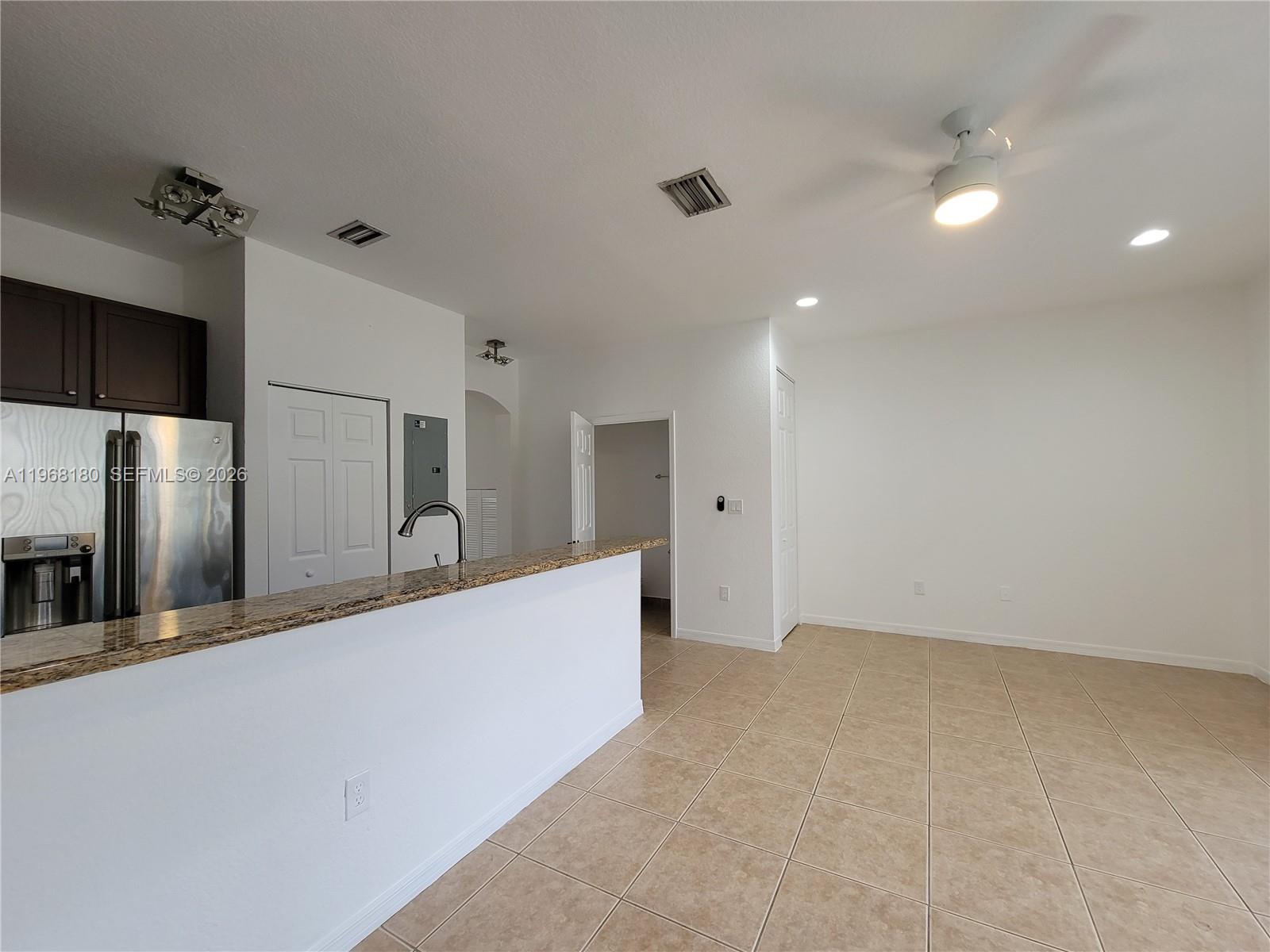 A kitchen with a granite breakfast bar, stainless steel refrigerator, and tile flooring — 8938 SW 19th St # 904, Miramar FL 33025, MIRAMAR, FL
