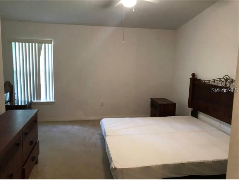 A bedroom features a bed with a wooden headboard, a dresser, and a window — 2792 CLUB CORTILE CIRCLE UNIT B, KISSIMMEE, FL