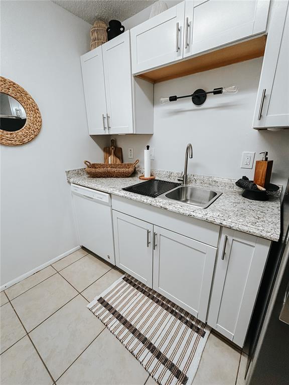 A kitchen area features white cabinets, granite countertops, a stainless steel sink, and tile flooring — 1600 BIG TREE ROAD UNIT O8, DAYTONA BEACH, FL