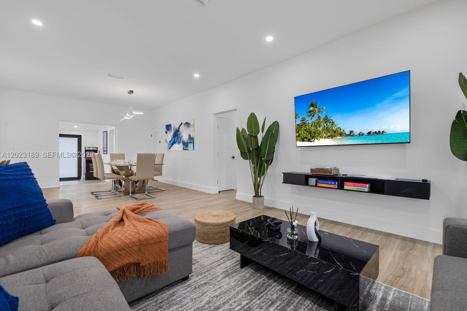 A modern living room features a gray sectional, black coffee table, and wall-mounted television — 121 NW 53rd St, Miami FL 33127, MIAMI, FL