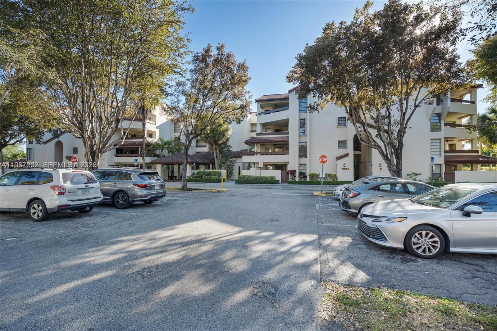 A parking lot sits in front of a multi-story residential apartment building with trees — 9040 SW 125th Ave # D408, Miami FL 33186, MIAMI, FL