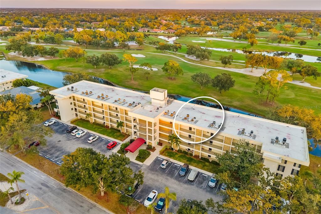 An aerial view shows a multi-story apartment building with a flat roof and parking lot — 7461 W COUNTRY CLUB DRIVE UNIT 404, SARASOTA, FL