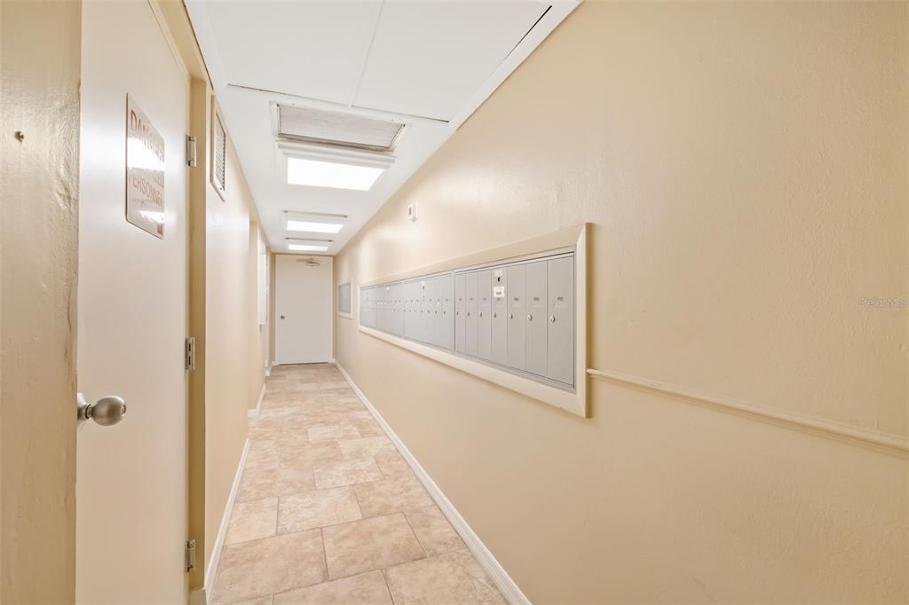 A hallway features a tiled floor, beige walls, and a wall-mounted bank of mailboxes — 7461 W COUNTRY CLUB DRIVE UNIT 404, SARASOTA, FL