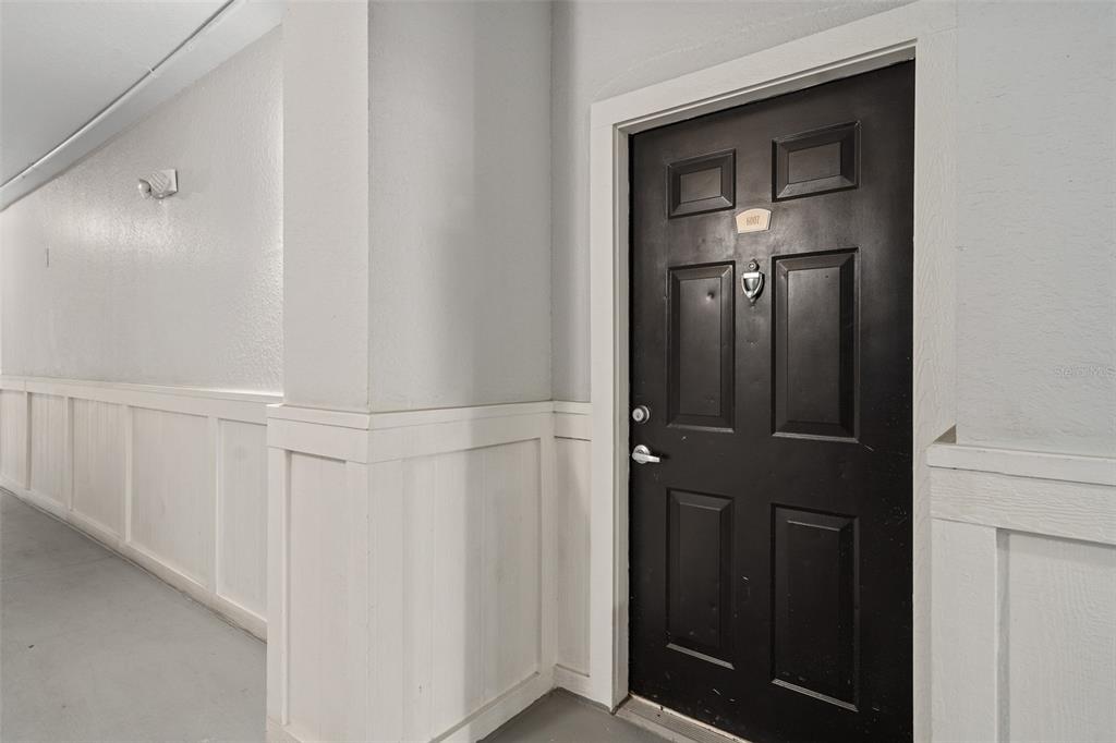 A black front door with a silver handle and knocker is set in a hallway — 206 E SOUTH STREET UNIT 6007, ORLANDO, FL
