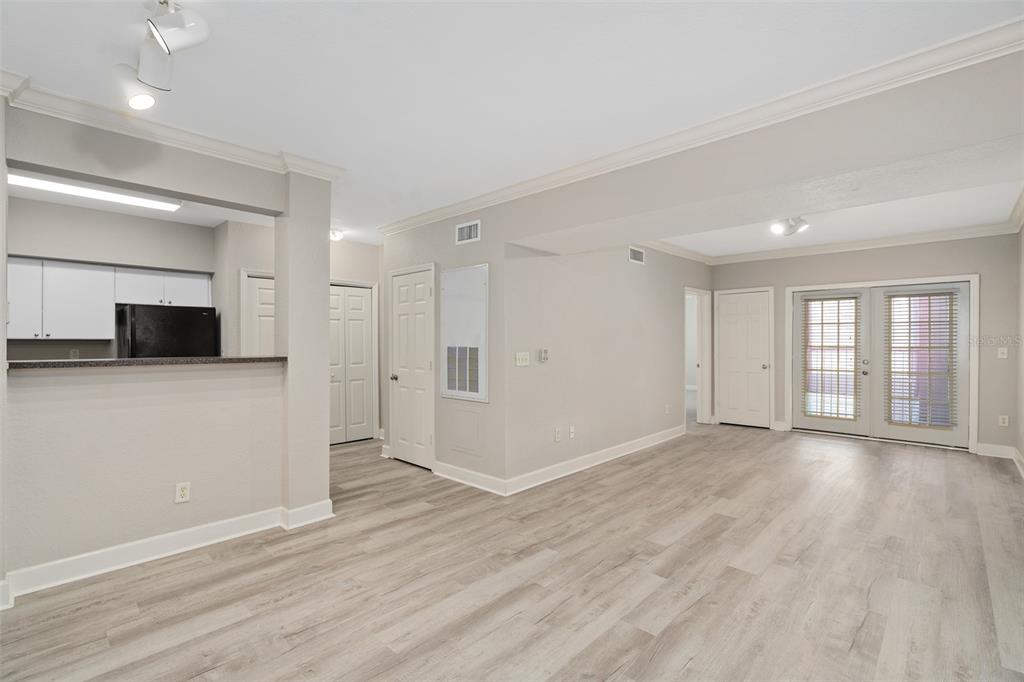 An open-concept living area features light wood-look flooring, neutral walls, and a kitchen pass-through window — 206 E SOUTH STREET UNIT 6007, ORLANDO, FL